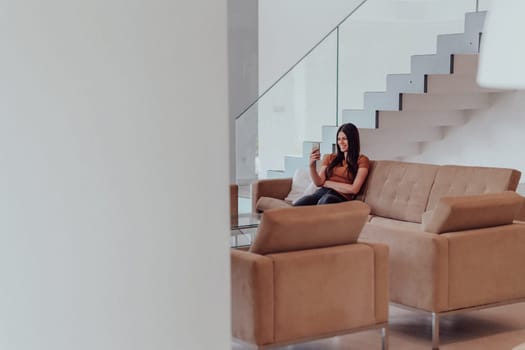 Woman using smartphone for video call while sitting in modern house. High quality photo