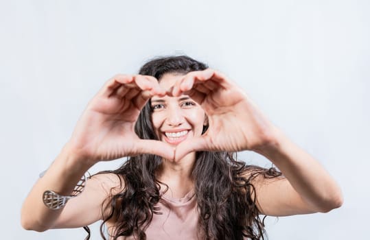 Happy girl making heart shape with hands isolated. Smiling young woman making heart shape with her hands. Teen girl making heart shape with her hands