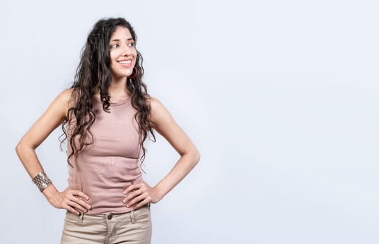 Thoughtful smiling girl looking at a blank space. Young woman looking at an advertisement to the side, Smiling girl with hands on waist looking at an advertisement