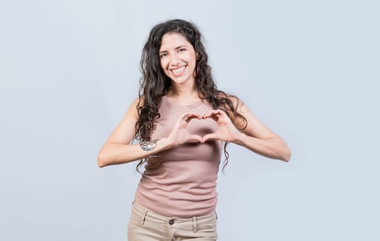 Smiling young woman making heart shape with her hands. Teen girl making heart shape with her hands, Happy girl making heart shape with hands isolated