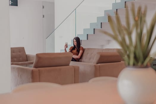 Woman using smartphone for video call while sitting in modern house. High quality photo