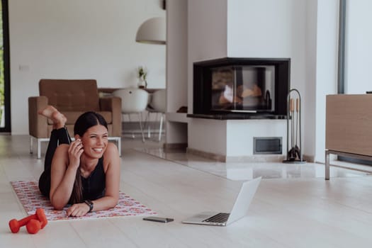 Young woman resting after online training while lying on the living room floor.