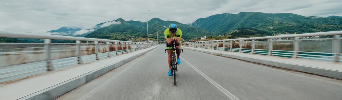 Full length portrait of an active triathlete in sportswear and with a protective helmet riding a bicycle. Selective focus .