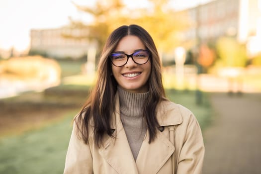 Cheerful LGBT female student wearing glasses joyfully smiling beautifully in front of campus.