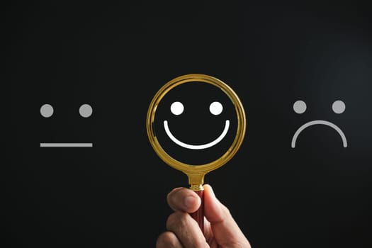 Magnifying glass reveals smiley face, finding happiness amid sadness on black. Customer satisfaction and evaluation after service survey. Magnification, satisfaction, reputation, corporate, customer