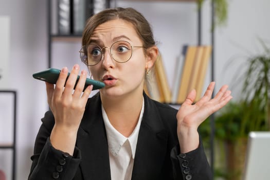 Caucasian business woman working, having mobile phone loudspeaker talk at office desk with laptop. Manager freelance happy girl holding smartphone using messenger chat apps. Employment, occupation