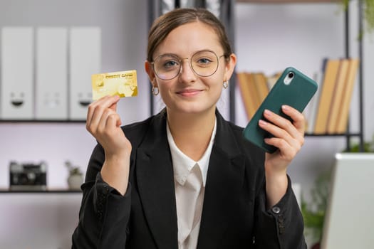 Joyful business woman programmer software developer working making online purchase payment shopping with credit bank card use laptop at home office desk with laptop. Caucasian freelancer pretty girl