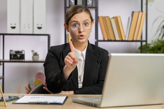 Caucasian young business woman working on laptop computer shakes finger, saying No be careful scolding and giving advice to avoid danger mistake disapproval sign at office. Confident freelancer girl