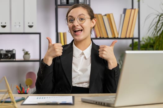 Like. Happy Caucasian business woman girl working on laptop looking approvingly at camera showing thumbs up, like sign positive something good, positive feedback at office workplace. Freelancer girl