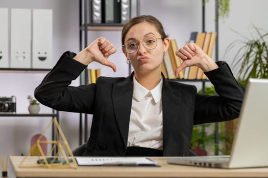 Dislike. Upset Caucasian business woman girl working on laptop computer at office thumbs down sign gesture, expressing discontent, disapproval dissatisfied bad work. Displeased serious freelancer girl