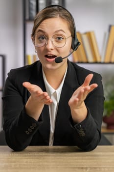 POV portrait of business woman wearing headset, freelance worker call center or support service operator helpline, having pleasant talk with client, colleague communication support at office. Vertical