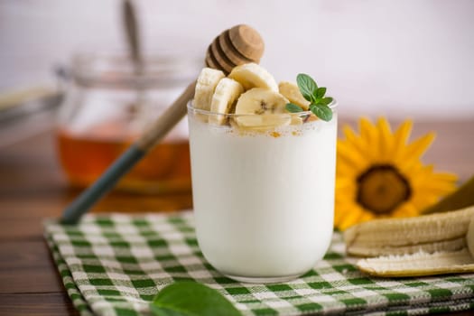 Sweet homemade yogurt with bananas and honey in a glass