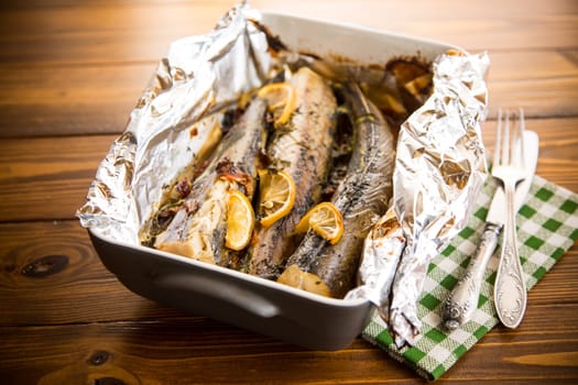 Baked fish with seasonings and spices in foil, in a ceramic form.