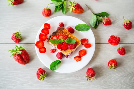 cooked cottage cheese casserole with berry and strawberry filling in a plate on the table