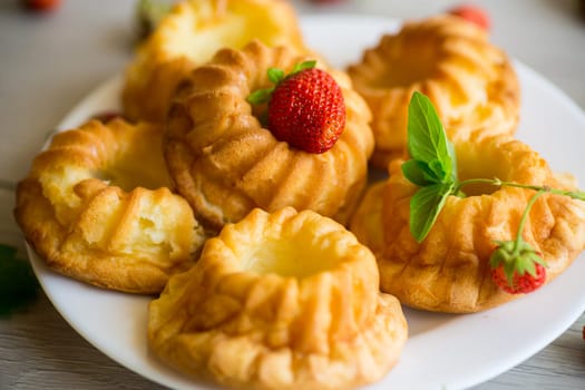 Cooked sweet curd cupcakes with fresh strawberries and mint on a wooden table.
