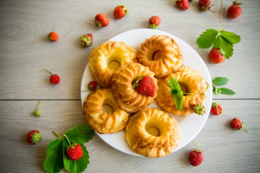 Cooked sweet curd cupcakes with fresh strawberries and mint on a wooden table.