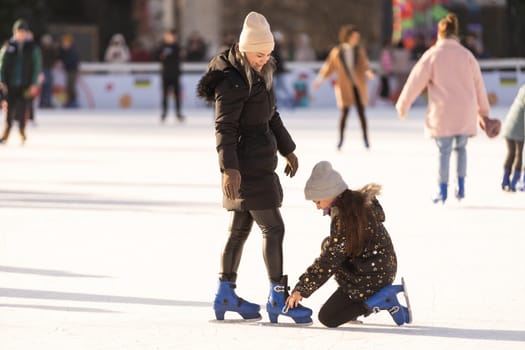 Adorable young mother with her daughter on the ice rink.