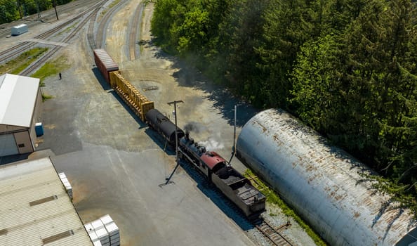 An Aerial View of a Steam Locomotive Moving Freight Cars Around in a Freight Yard to Organize a Freight Train on a Sunny Day