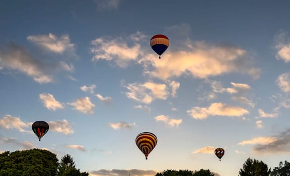 A View of Multiple Multi Colored Hot Air Balloons Floating in a Beautiful Morning Blue Sky With Thin Clouds
