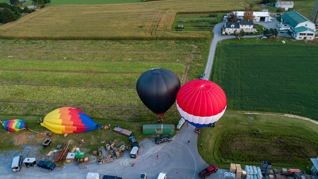 A Drone View of Multiple Colorful Hot Air Balloons Landing in Farms Fields, Parking Lots and Homes on a Beautiful Sunny Summer Afternoon