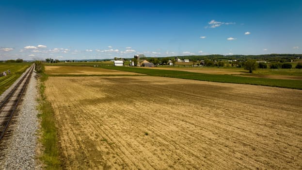 An Aerial View of a Plowed Field with a Barn, Silos and Farm House in View on a Spring Day