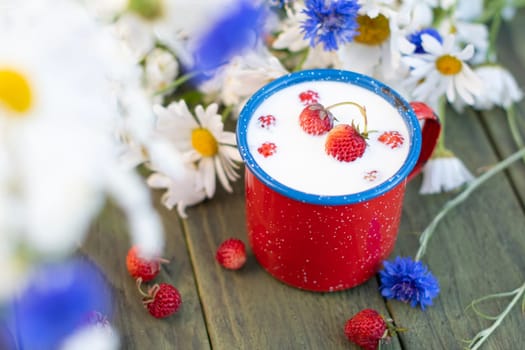 Fresh Strawberry with cold milk in red mug on wild flowers background,childhood nostalgia Healthy fruit dessert, food and drink, High quality photo