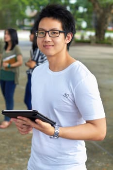 Asian man, college student and tablet in outdoor portrait with smile for study, education and social media app. Japanese gen z person, digital touchscreen and learning at university, campus or school.