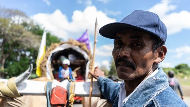 Latin American peasant watching camera with his oxcart pulled by oxen in the background