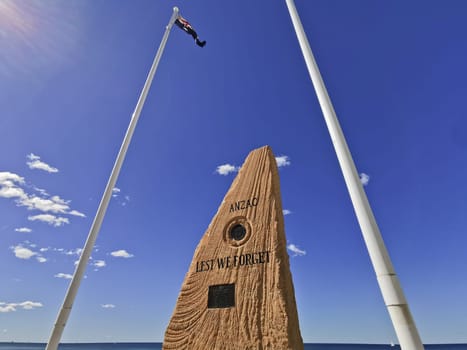 GOLD COAST, AUSTRALIA - AUGUST 16, 2020: Surfers Paradise Esplanade ANZAC War Memorial Stone between 2 flag poles and the text 'Lest We Forget'. This stone is located at Surfer Paradise beach. There is no body in the photo.