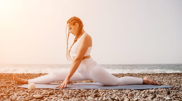 Woman yoga sea. Well looking middle aged woman with braids dreadlocks in white leggings and tops doing stretching pilates on yoga mat near sea. Female fitness yoga routine concept. Healthy lifestyle