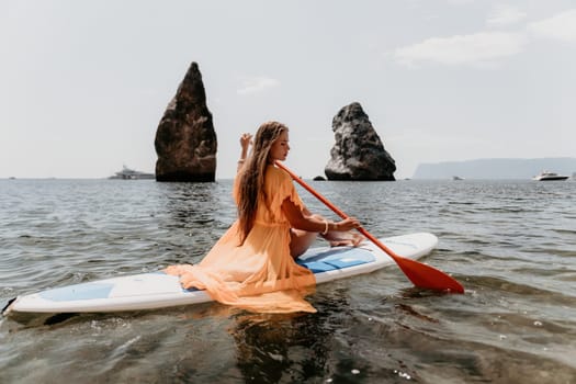 Close up shot of beautiful young caucasian woman with black hair and freckles looking at camera and smiling. Cute woman portrait in a pink bikini posing on a volcanic rock high above the sea