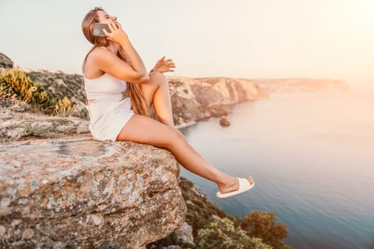 Woman travel sea. Young Happy woman in a long red dress posing on a beach near the sea on background of volcanic rocks, like in Iceland, sharing travel adventure journey