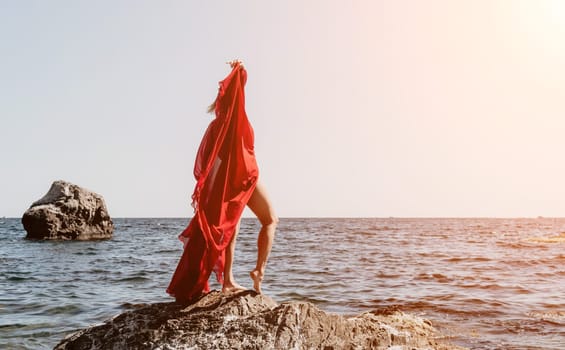 Woman travel sea. Young Happy woman in a long red dress posing on a beach near the sea on background of volcanic rocks, like in Iceland, sharing travel adventure journey