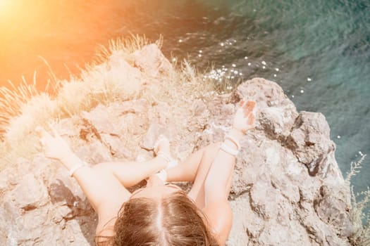 Woman meditating in yoga pose silhouette at the ocean, beach and rock mountains. Motivation and inspirational fit and exercising. Healthy lifestyle outdoors in nature, fitness concept.