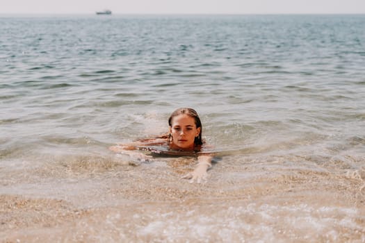 Woman travel sea. Young Happy woman in a long red dress posing on a beach near the sea on background of volcanic rocks, like in Iceland, sharing travel adventure journey