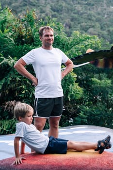 Happiness with dad. Father's Day. Raising son. Man smiling standing hands at waist by sides, boy child lying. I wish happiness, peace in the soul and mind to everyone who is looking at this photo.