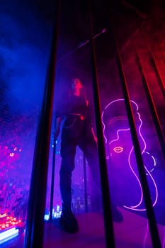 Caucasian woman in neon studio behind steel bars