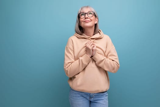 dreamy fashionable mature woman in youth outfit on studio background with copy space.