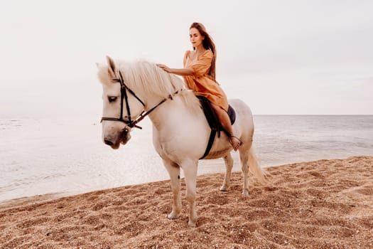 A woman in a dress stands next to a white horse on a beach, with the blue sky and sea in the background