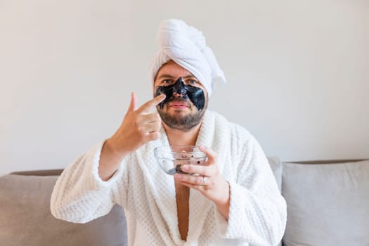 funny bearded man applying black mask for skin care