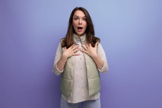 surprised young brunette woman on purple background.