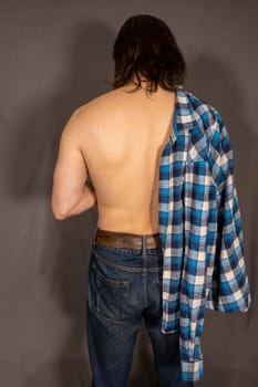 Portrait of a sexy young man with muscular body posing at studio. Gray background. Men's health. High quality photo