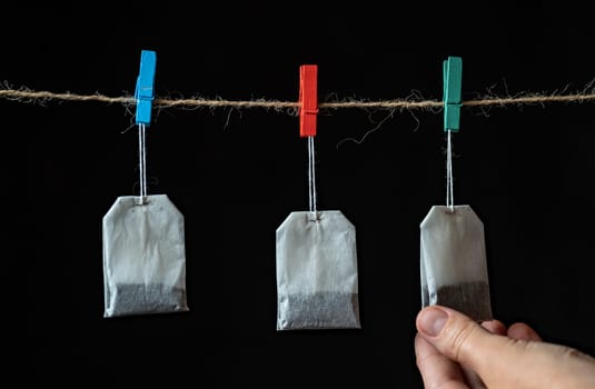 White Tea bags Isolated on black background holding on rope, hand pick one. Select best one . best choose of tea concept
