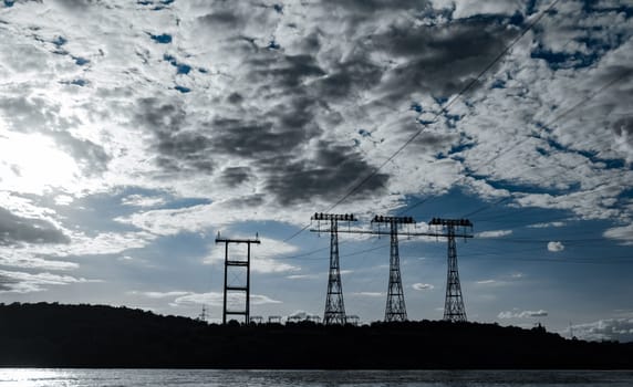 high voltage poles. high voltage post. high voltage tower by the river. industry