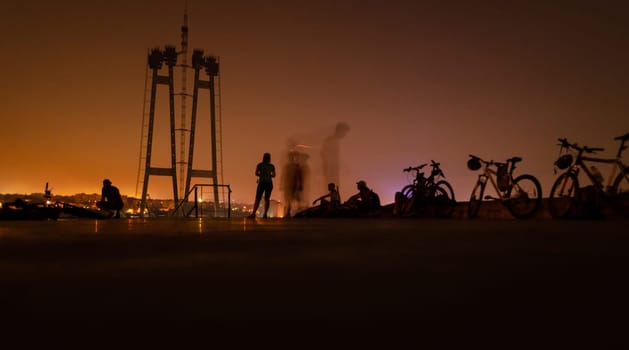 Cycling outdoor adventure. bikes with people night landscape. Outdoor sport activity. silhouette of group people with bicycles on industrial background