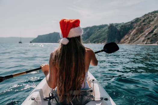 Woman in kayak back view. Happy young woman with long hair floating in transparent kayak on the crystal clear sea. Summer holiday vacation and cheerful female people relaxing having fun on the boat