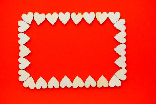 Valentine's day background. Wooden hearts are lined with rectangle on a red background with place for text with hearts. Hearts for postcards.