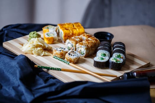 Set of traditional japanese food on a dark background. Sushi rolls, nigiri, raw salmon steak, rice, cream cheese, avocado, lime, pickled ginger. Asian food frame.
