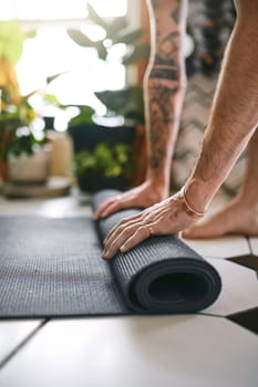Yoga keeps you grounded. an unrecognisable man rolling up his yoga mat at home