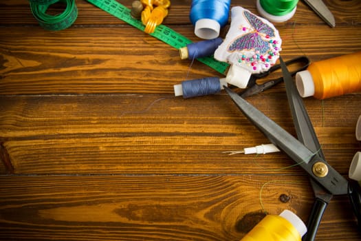 a set of tools and threads for sewing clothes, on a wooden background.